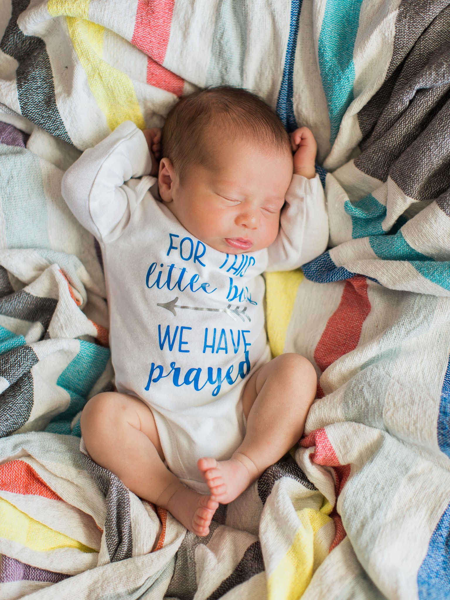 a photo taken to symbolize that he was a rainbow baby with a brightly colored blanket behind him by j. photography
