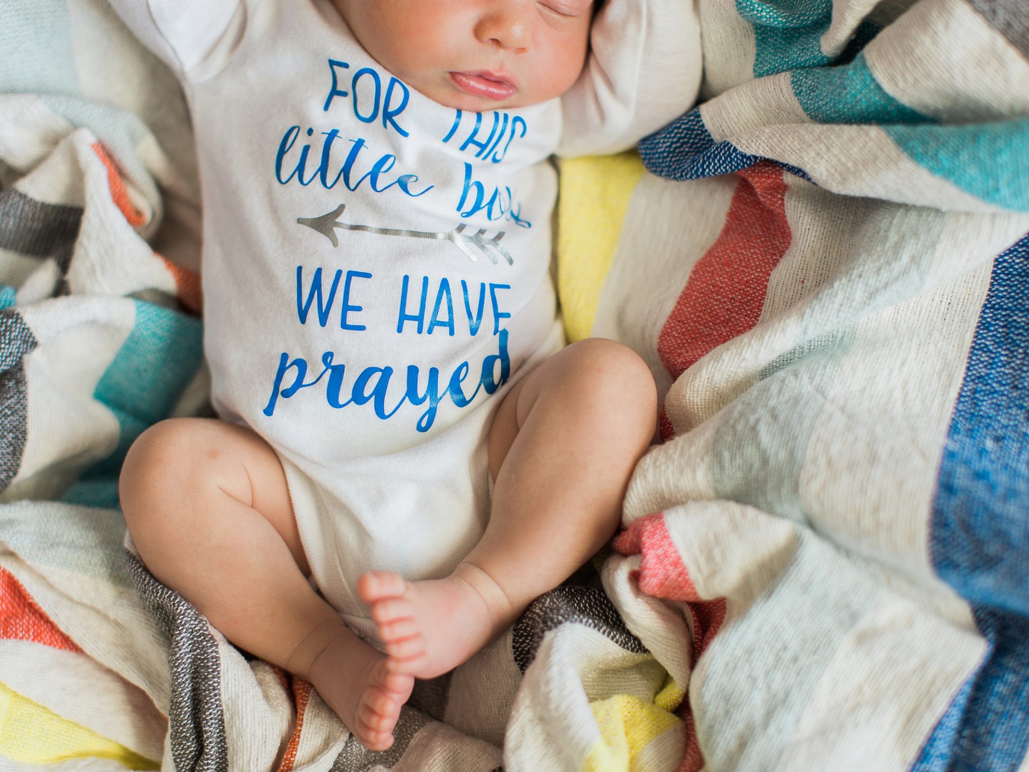 a photo taken to symbolize that he was a rainbow baby with a brightly colored blanket behind him by j. photography